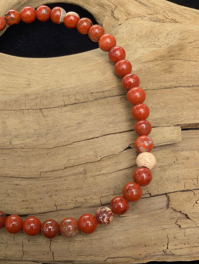 Macro close-up of 4mm polished Red Jasper beads highlighting the high-gloss finish and natural red hematite inclusions.