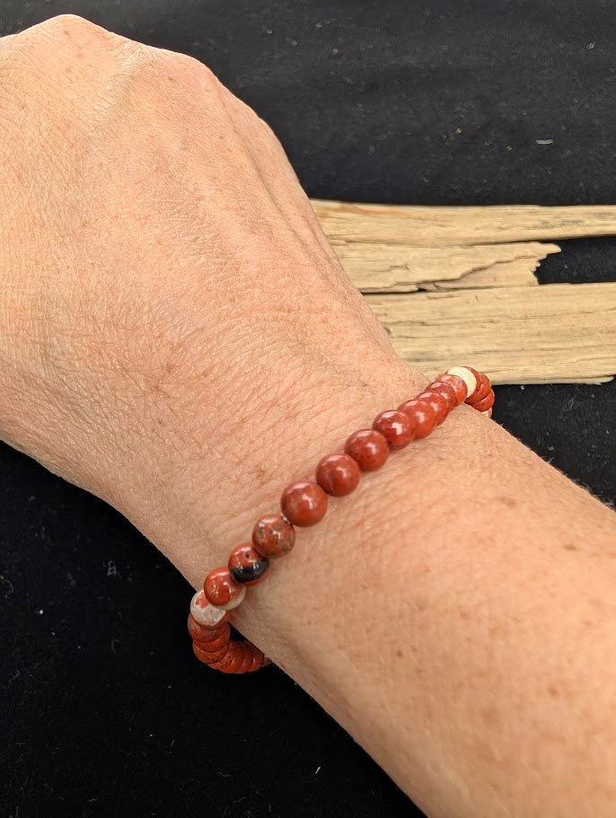 4mm polished Red Jasper beaded stretch bracelet worn on a wrist for delicate size scale.