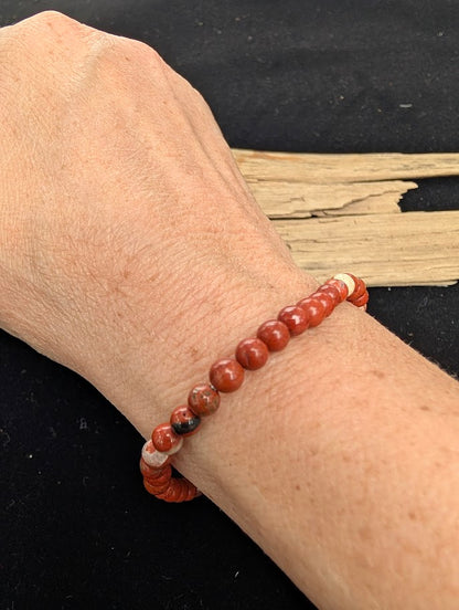 4mm polished Red Jasper beaded stretch bracelet worn on a wrist for delicate size scale.