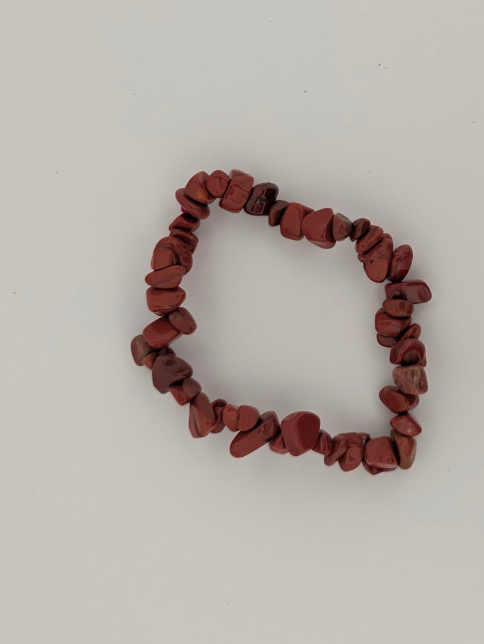 Top-down view of red jasper chip bracelet on a white background