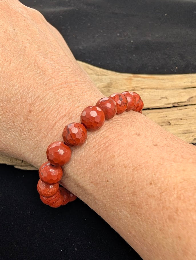 8mm faceted Red Jasper beaded stretch bracelet worn on a wrist for size scale.