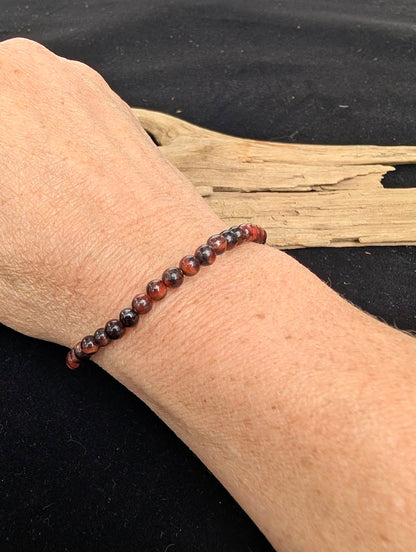 4mm polished Red Tiger Eye beaded stretch bracelet worn on a wrist for delicate size scale.