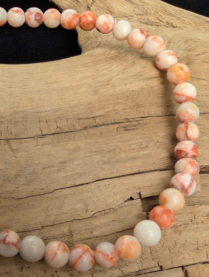 Macro close-up of 4mm polished Red Vein Jasper beads highlighting the high-gloss finish and natural red, web-like brecciated patterns.