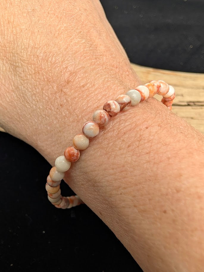 4mm polished Red Vein Jasper beaded stretch bracelet worn on a wrist for delicate size scale.
