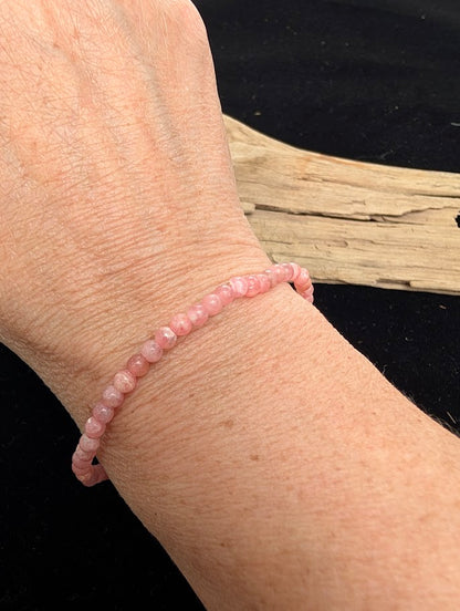4mm AA-grade polished Rhodochrosite beaded stretch bracelet worn on a wrist for delicate size scale.