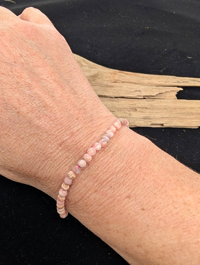 4mm A-grade polished Rhodochrosite beaded stretch bracelet worn on a wrist for delicate size scale.