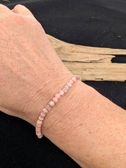 4mm A-grade polished Rhodochrosite beaded stretch bracelet worn on a wrist for delicate size scale.