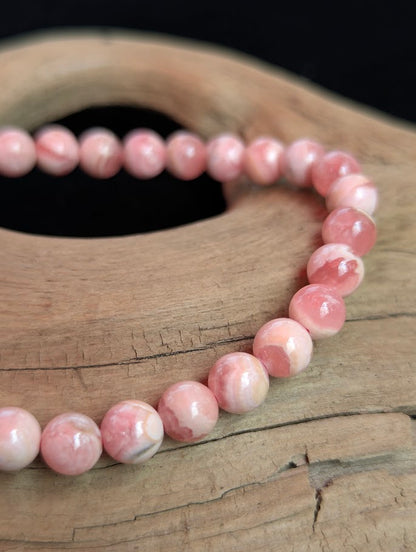 Macro close-up of a 6mm Argentinian Rhodochrosite beaded bracelet showing refined polish and delicate pink and white banding.