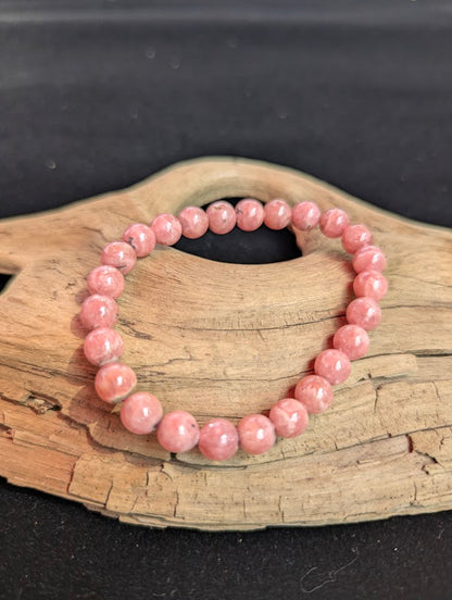 Macro view of a 7mm Argentinian Rhodochrosite beaded bracelet highlighting smooth spherical lapidary polish and natural growth patterns.
