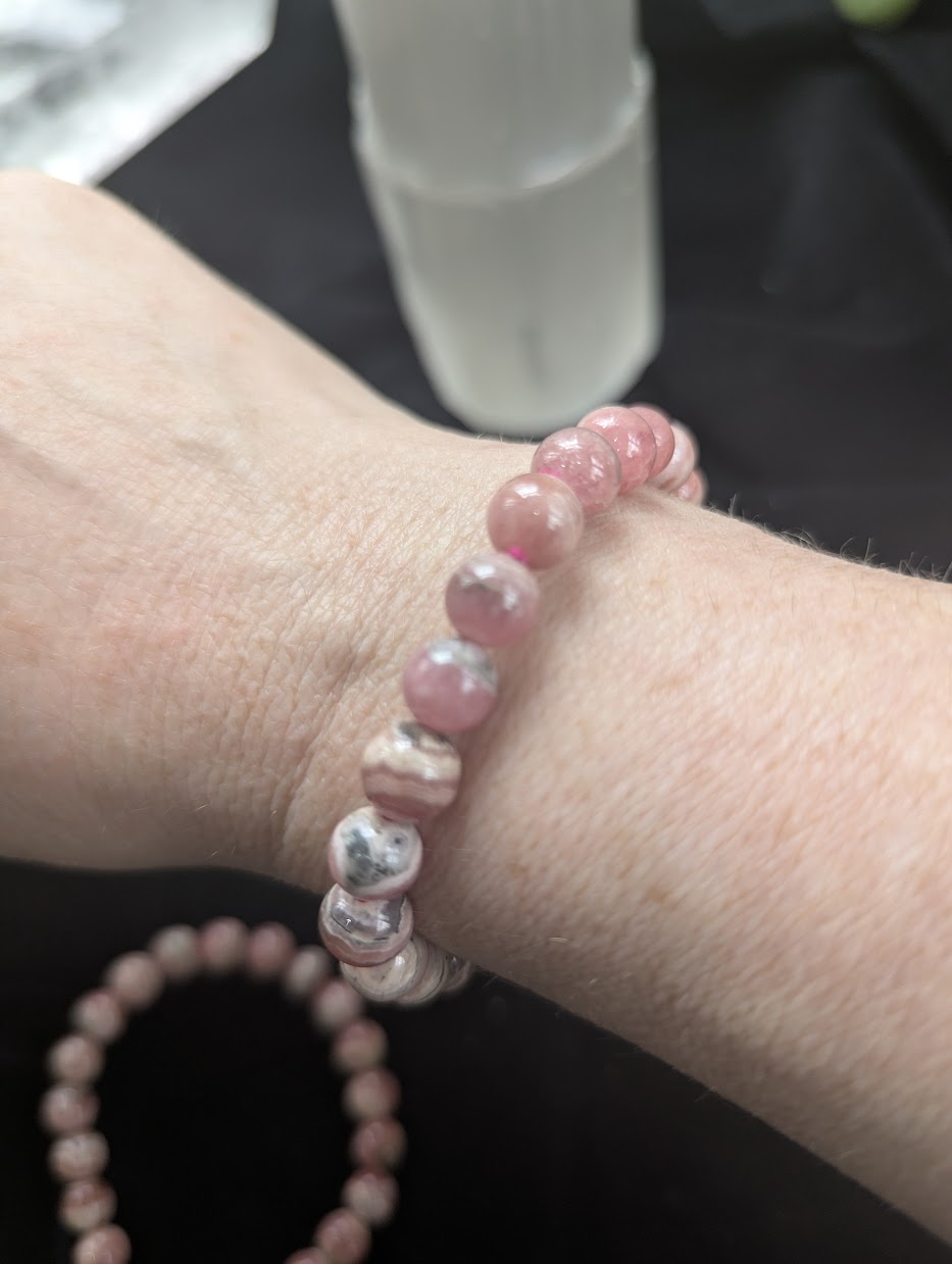 8mm Argentinian Rhodochrosite beaded bracelet worn on a wrist to demonstrate scale, fit, and natural colour variation.