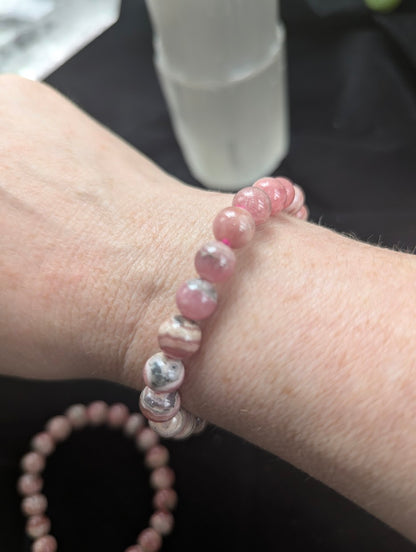 8mm Argentinian Rhodochrosite beaded bracelet worn on a wrist to demonstrate scale, fit, and natural colour variation.
