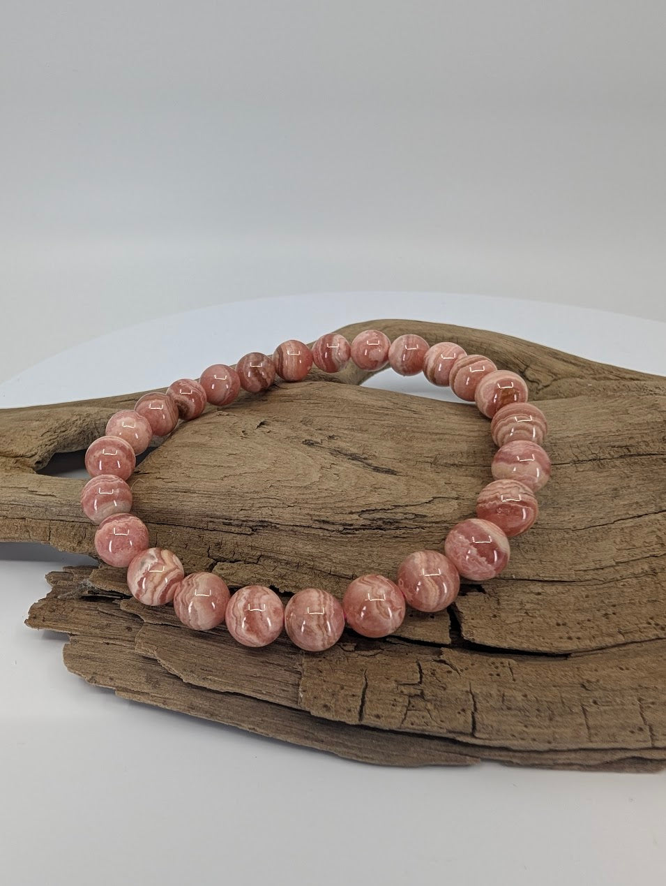 8mm rhodochrosite bracelet on wood displaying natural pink banding
