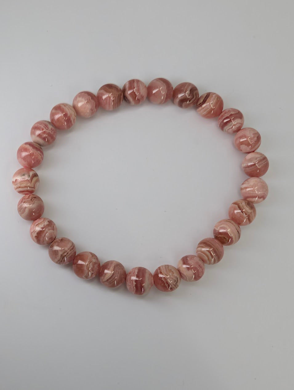 Overhead view of natural rhodochrosite bracelet arranged in a circle