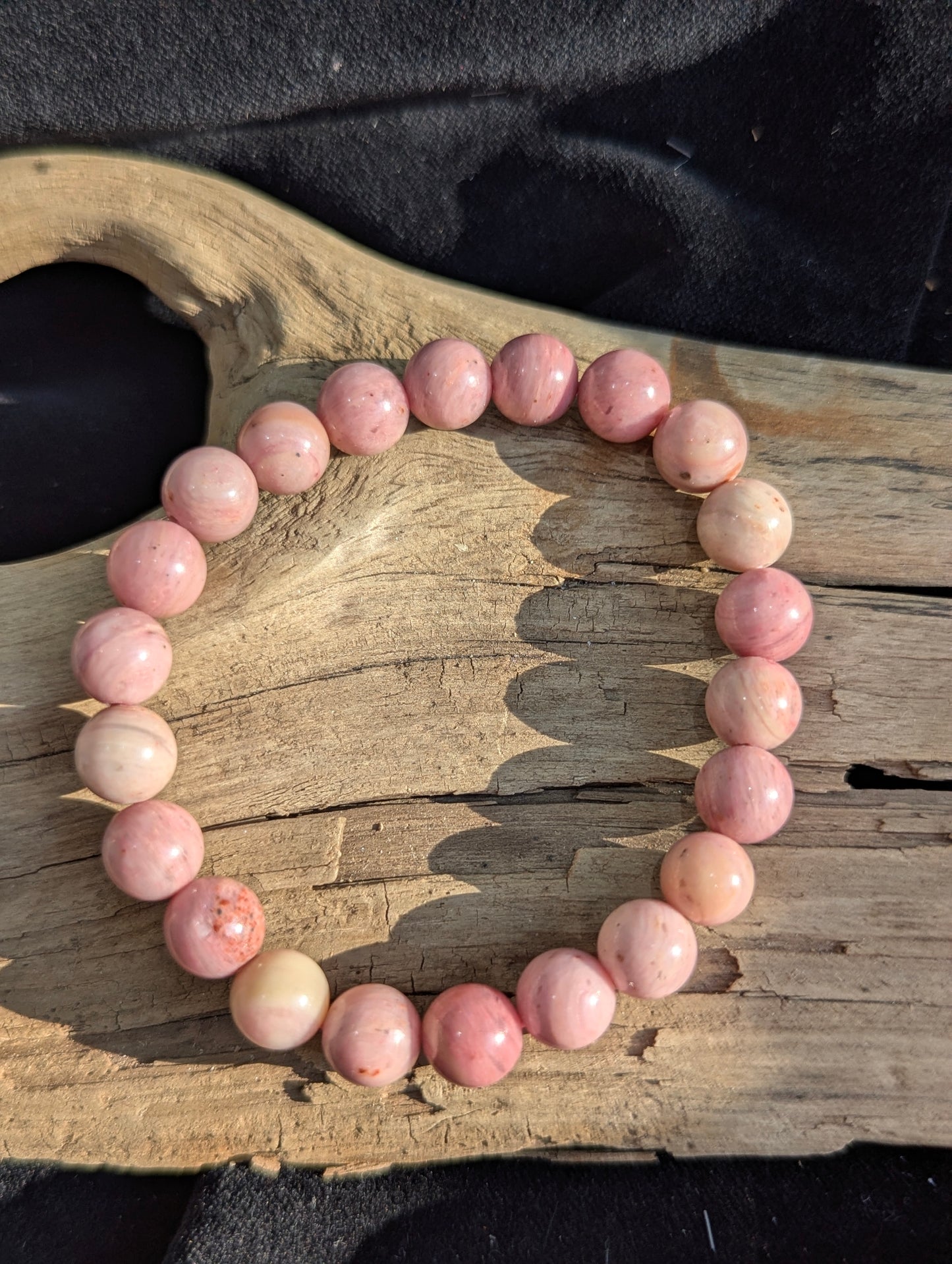 An 8mm Blush Rhodonite round bead stretch bracelet positioned on a flat presentation surface, demonstrating bead uniformity, precise lapidary polish, and a soft pink groundmass.