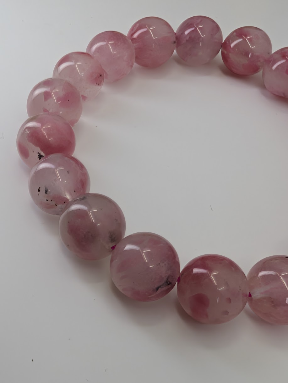 Madagascar rhodonite bracelet featuring 11 millimeter beads with natural quartz-hosted translucency