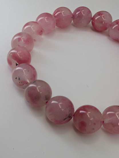 Madagascar rhodonite bracelet featuring 11 millimeter beads with natural quartz-hosted translucency