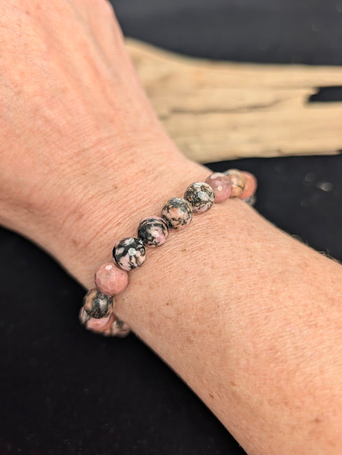 8mm faceted Rhodonite beaded stretch bracelet worn on a wrist for size scale.