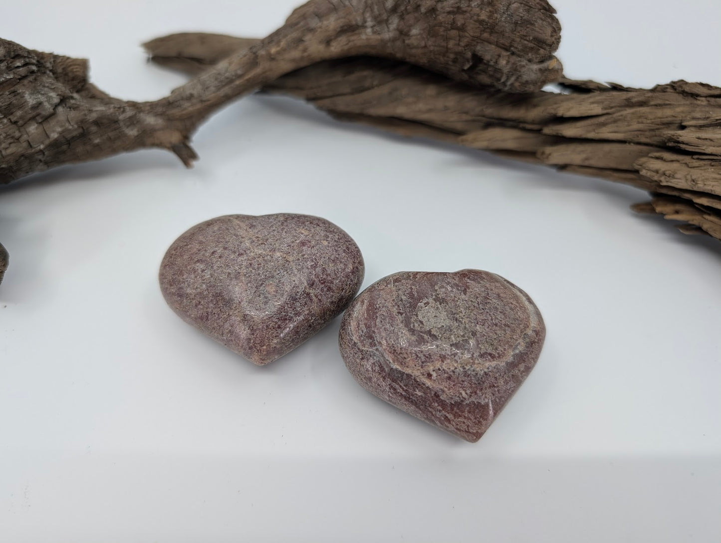 Pair of polished Rhodonite hearts showing dusty rose and mauve colors.