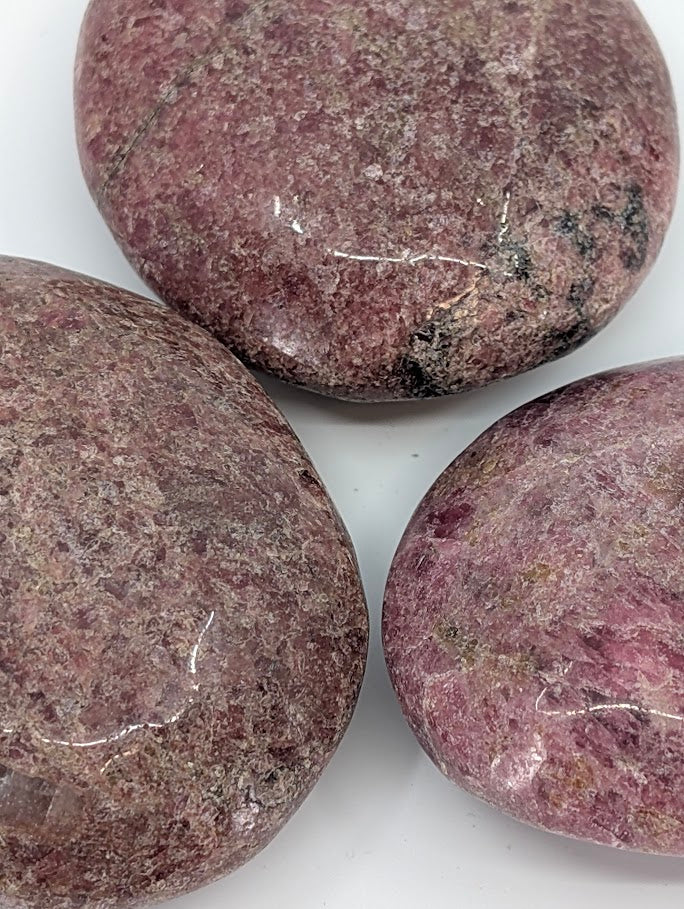 Close-up of rhodonite palm stone displaying fine crystalline texture and natural inclusions