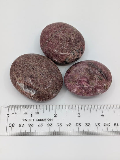 Rhodonite palm stones with measuring scale showing size and polish detail