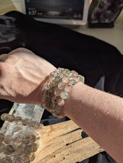 On wrist display of AA-grade Brazilian black and red copper rutilated quartz stretch bracelets showcasing varying bead sizes and high-clarity polish.