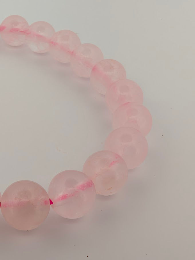 Detail of 8mm rose quartz bracelet with pastel pink tone and smooth polish