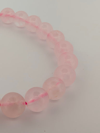 Detail of 8mm rose quartz bracelet with pastel pink tone and smooth polish