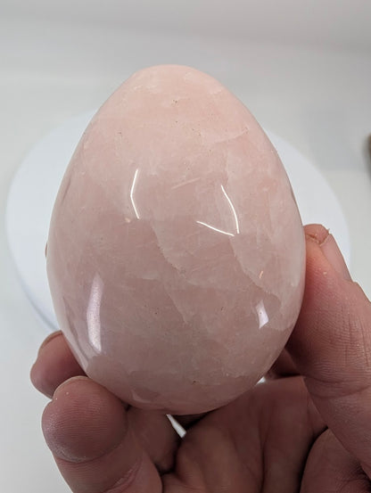 Hand-held rose quartz egg highlighting natural pink tones and organic internal patterning