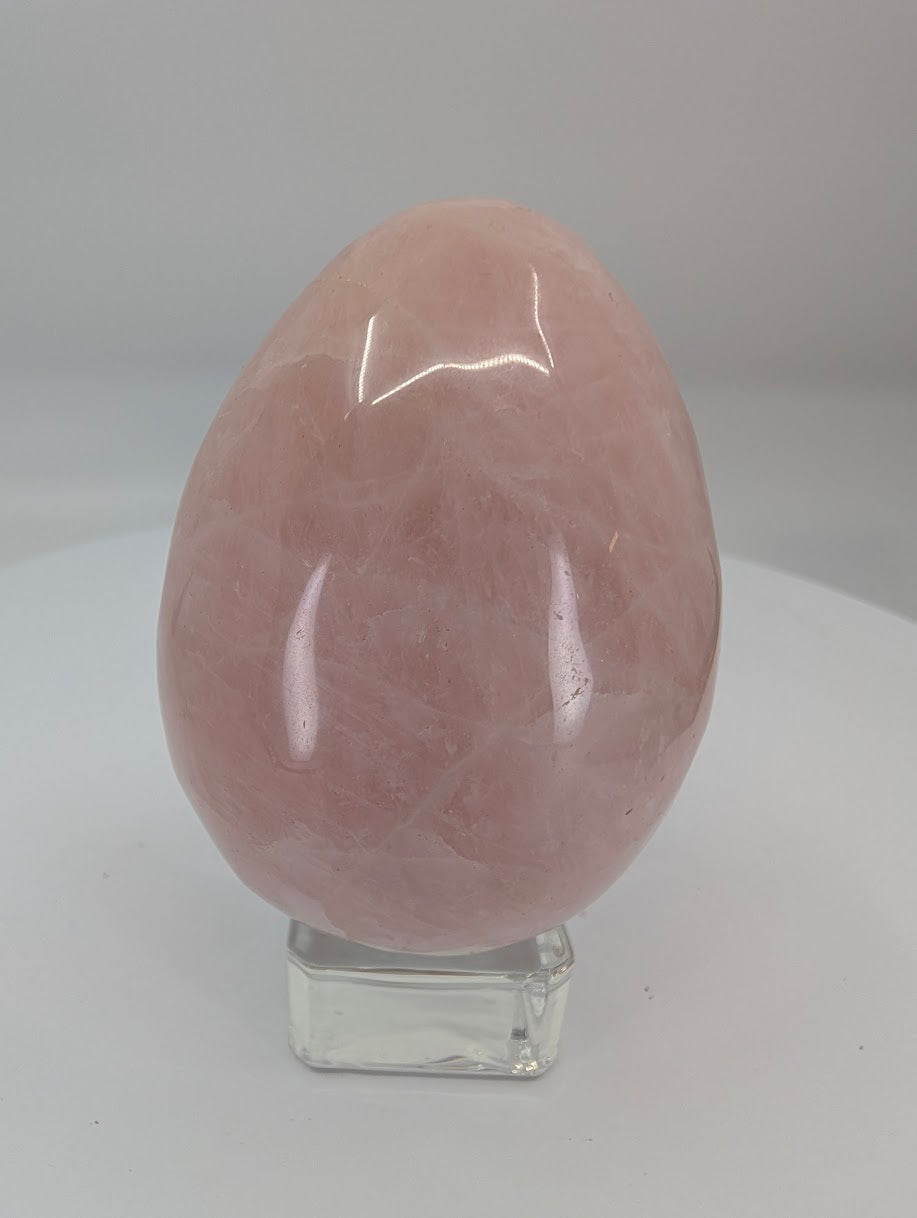 Side view of a polished rose quartz egg showing internal veils and smooth polished surface