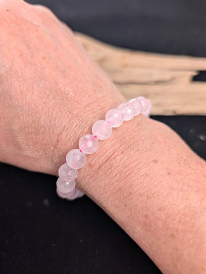 8mm faceted Rose Quartz beaded stretch bracelet worn on a wrist for size scale.