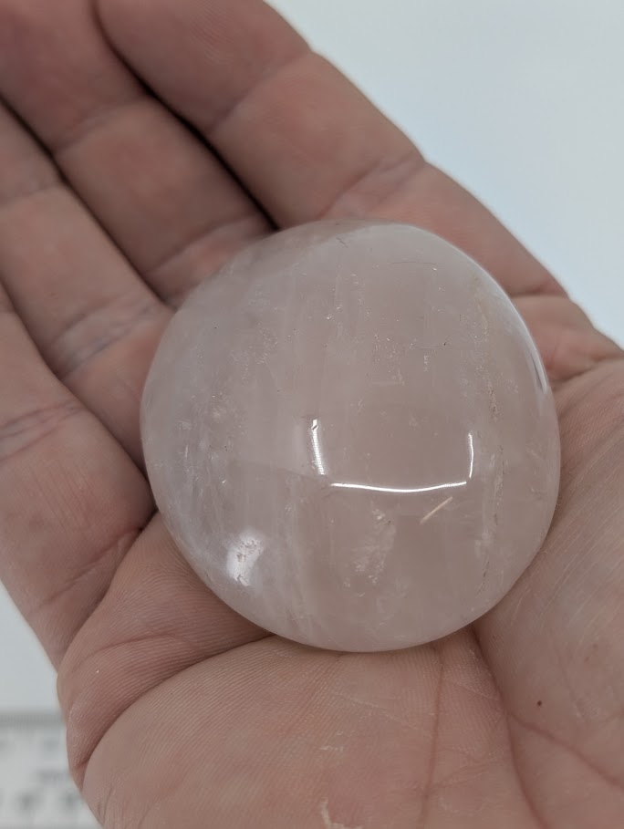 Rose Quartz palm stone in hand showing pale pink color, polished finish, and gentle translucence