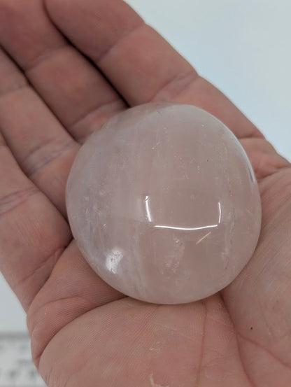 Rose Quartz palm stone in hand showing pale pink color, polished finish, and gentle translucence
