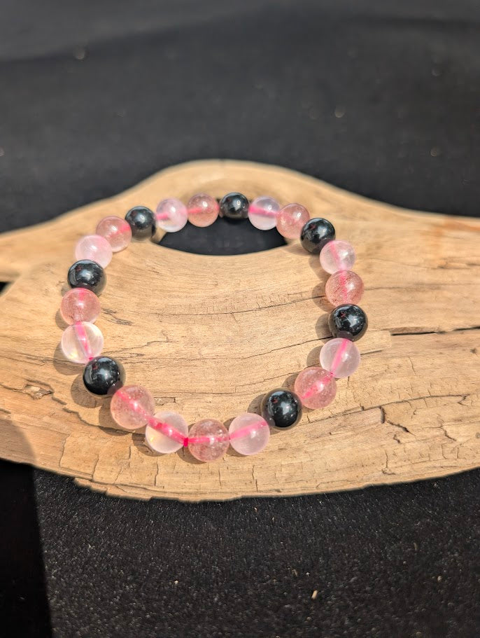 8mm Rose Quartz, Strawberry Quartz, and Obsidian beaded bracelet resting on driftwood display.