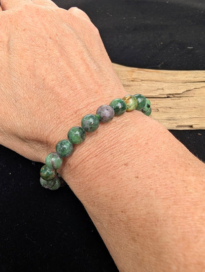 8mm polished Ruby in Fuchsite beaded stretch bracelet worn on a wrist for size scale.