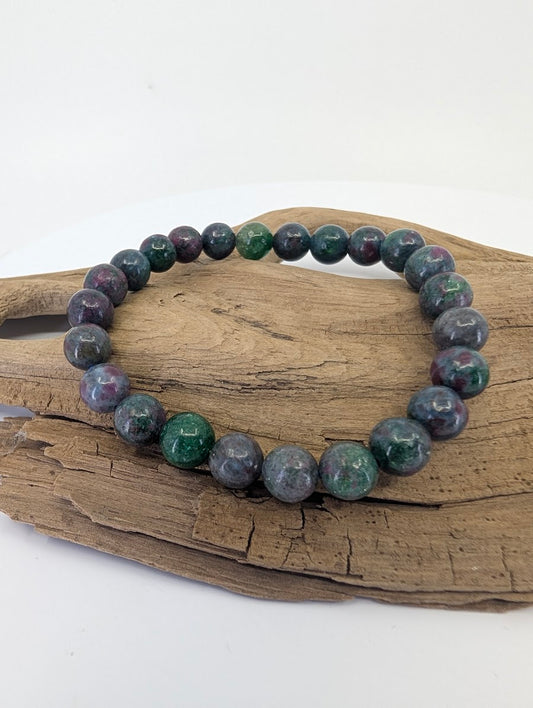 8mm Ruby in Blue Kyanite bead bracelet from India displayed on driftwood showing deep blue and magenta tones.