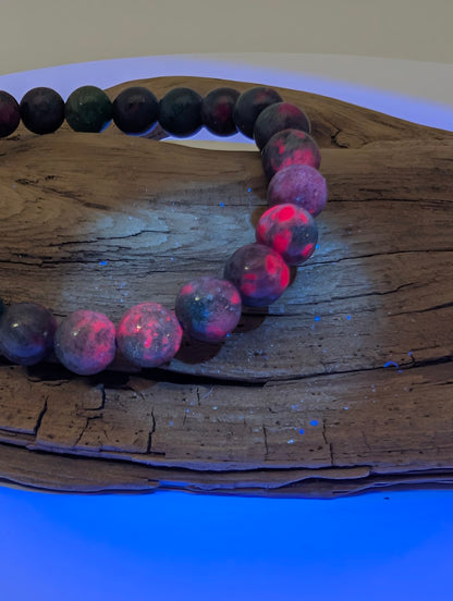 8mm Ruby in Kyanite bracelet under UV light showing vibrant neon-pink fluorescence of natural Ruby crystals.