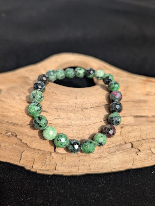 8mm faceted Ruby in Zoisite beaded stretch bracelet resting on a driftwood display, showing green and red contrast.