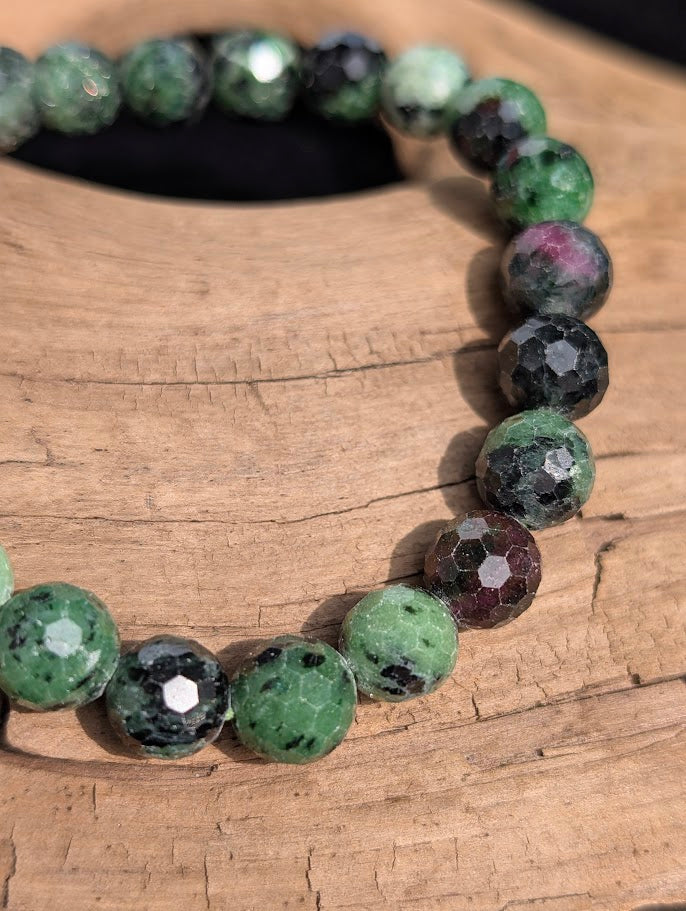 Macro close-up of 8mm faceted Ruby in Zoisite beads highlighting the geometric surface cuts and natural ruby inclusions.