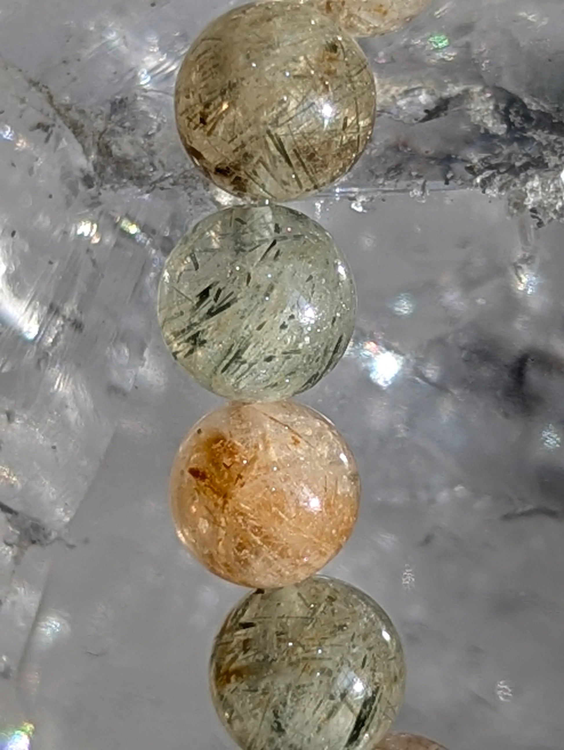 Macro detail of individual 7mm beads showing needle-like rutile inclusions and quartz transparency.