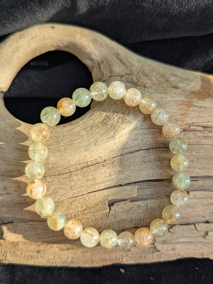 Single 7mm Rutilated Quartz bracelet on textured driftwood surface.