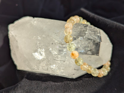 Close-up of 7mm Rutile Quartz bracelet encircling a clear quartz specimen.