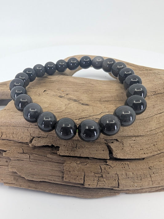 Saffordite bracelet with 8mm polished beads displayed on driftwood