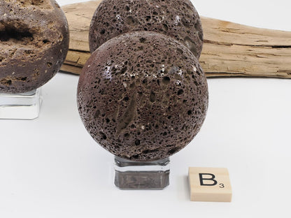 Specimen B: A 56mm polished volcanic Scoria sphere with earthy basaltic tones and natural porous surface.