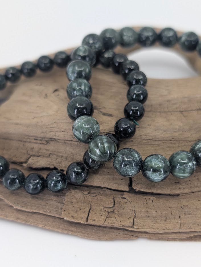 Close-up of Seraphinite beads displaying chatoyant mica inclusions