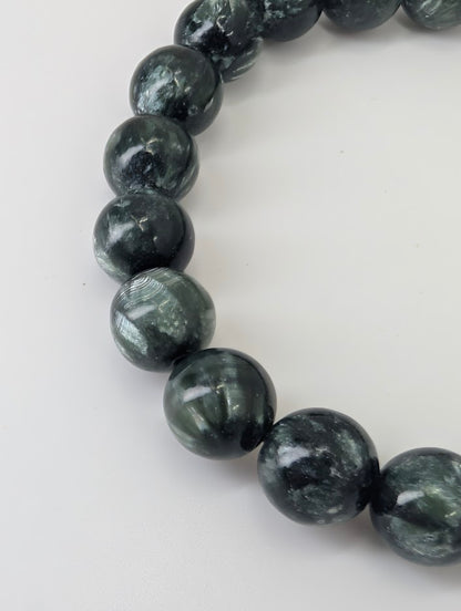 Close-up of Seraphinite beads displaying chatoyant mica inclusions