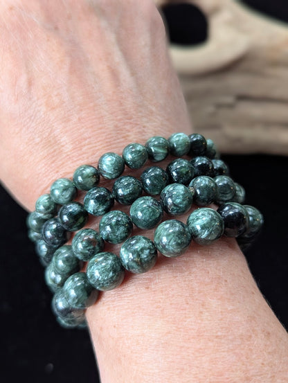 Multiple Seraphinite (Clinochlore) Bracelets of varying sizes stacked together on a wrist.