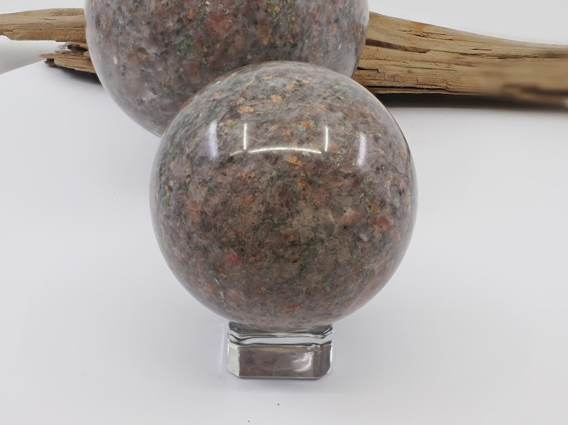 Small 60mm Sesame Jade sphere, polished natural stone with black biotite and red garnet spots.