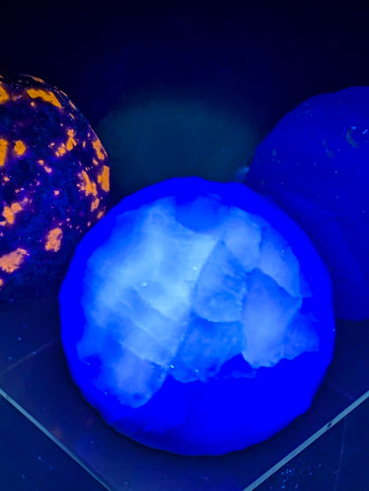 A 50 mm (1.97 in) Silk Fluorite carved moon sphere displaying UV effect