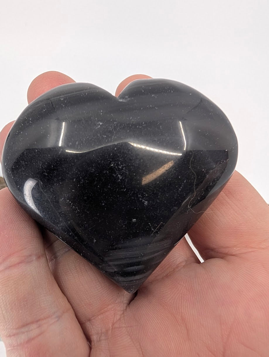 Hand holding a 70g Silver Sheen Obsidian heart showing metallic shimmer.