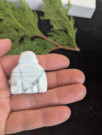 Rear view of a white Howlite Laughing Buddha carving showing robe details.